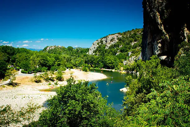 River Ardeche near the famous natural landmark of the Pont D'Arc with tourists canoeing in the river in the background.