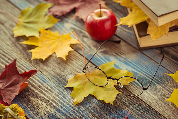 istock Eye glasses with book and autumn leaves on table 621354014