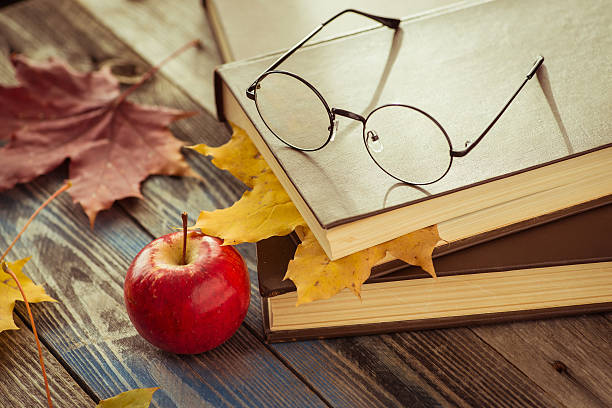 istock Eye glasses with book and autumn leaves on table 621354112