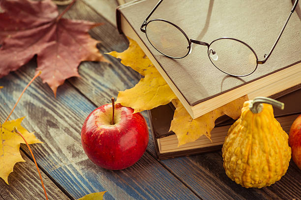 istock Eye glasses with book and autumn leaves on table 621354252