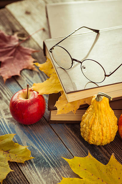 istock Eye glasses with book and autumn leaves on table 621354342