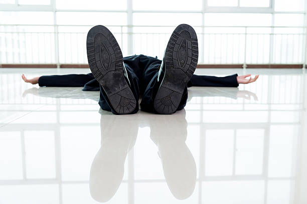 Exhausted businessman lying down on office lobby floor. Focused on the soles.