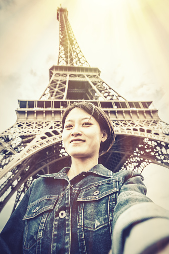 Young chinese female tourist in front of the Eiffel Tower