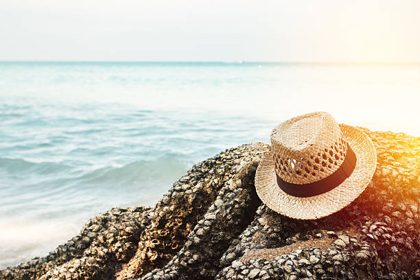 Vacation concept. Hat lying on a stone near sea coast.