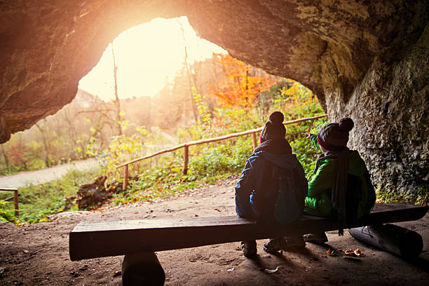 Little boys hiking in autumn. The boys are sitting in a cave opening looking at view, Boys are aged 7 and are resting in a small cave.