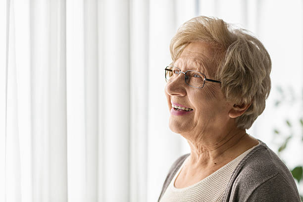 istock Elderly woman looking through a window 621361740