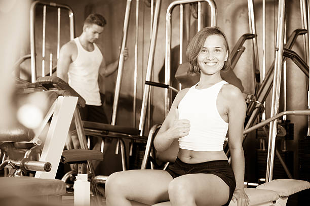 istock Woman sitting on bench between exercises in gym 621362576