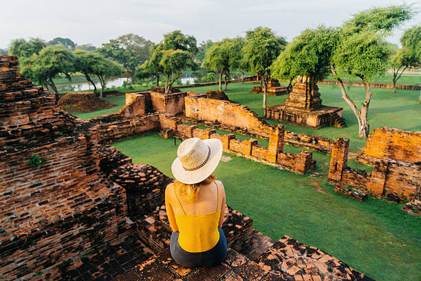 istock Woman sitting and looking at ancient Buddhist Temple 621363044