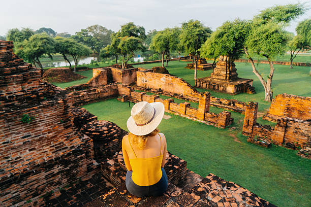 Woman sitting and looking at ancient Buddhist Temple Young Caucasian woman sitting near the ruins of ancient Buddhist Temple, Ayutthaya, Thailand ayuthaya photos stock pictures, royalty-free photos & images
