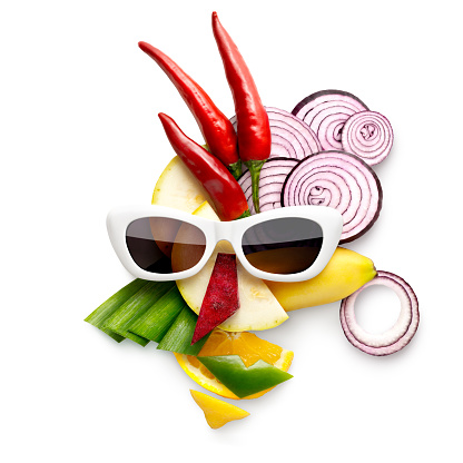 Quirky food concept of cubist style female face in sunglasses made of fruits and vegetables, on white.