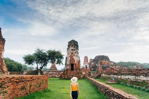 Young Caucasian woman walking near the ruins of ancient Buddhist Temple, Ayutthaya, Thailand