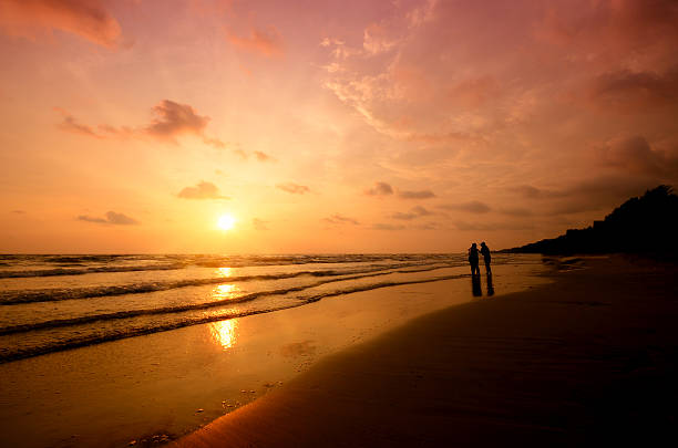 The friend playing on the beach at the sunset time