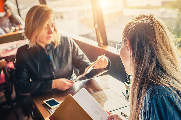 Two girlfriends in restaurant choosing food in menu