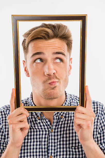 istock Man holding a picture frame in front of his face 621366820