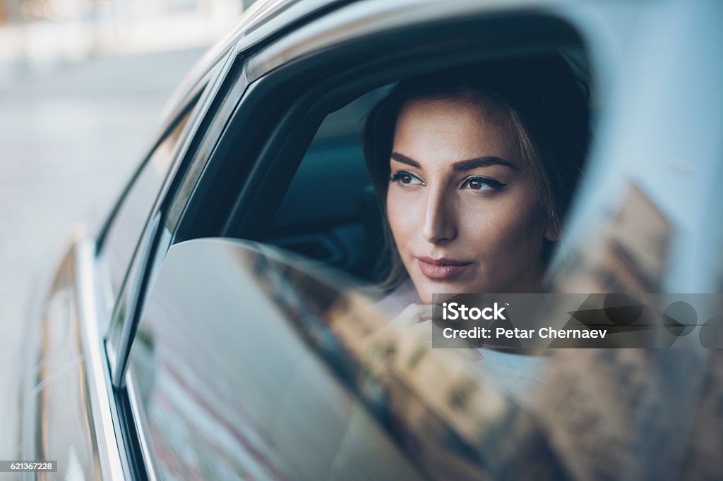 Femme sérieuse regardant par la fenêtre d’une voiture - Photo de Luxe libre de droits