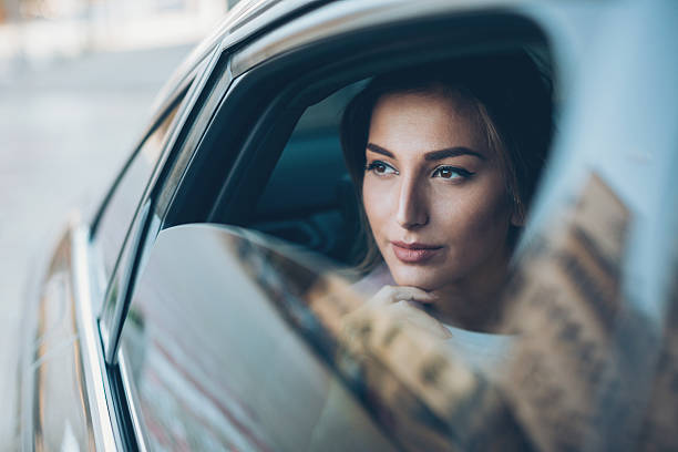 donna seria che guarda fuori dal finestrino di un'auto - high society foto e immagini stock