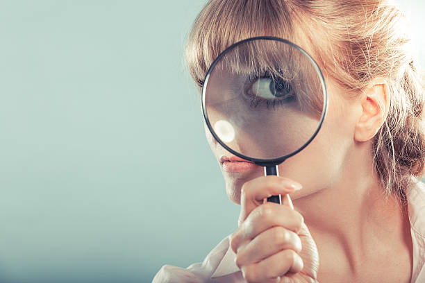 istock Woman hand holding magnifying glass on eye 621369228