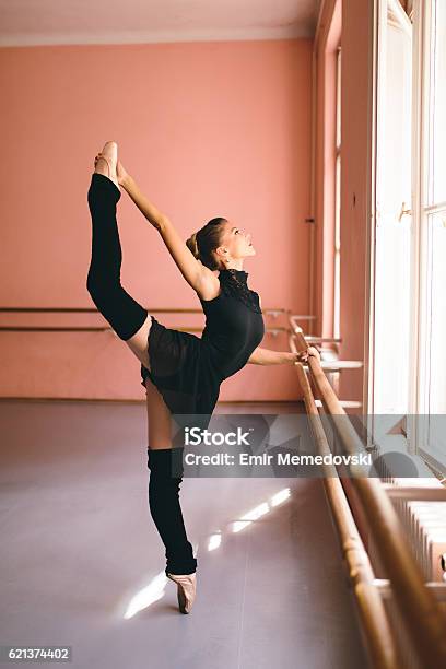 Young Ballerina Tip Toeing Next To A Barre Stock Photo - Download Image Now - Leg Warmers, Ballet, Dancing