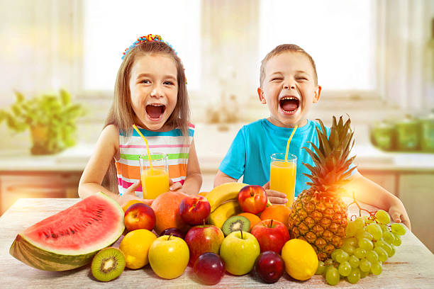 キッチンでフルーツとフレッシュジュースを持つ子供たち, 健康的な食事 - healthy lifestyle people eating sister ストックフォトと画像
