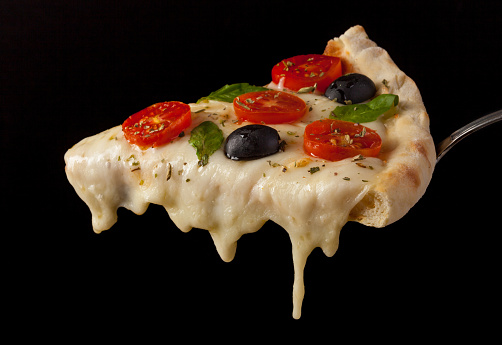 A hot pizza slice with dripping melted cheese. Isolated on black.