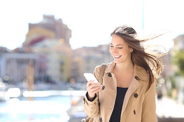 istock Happy woman walking and writing on a smart phone 621378986
