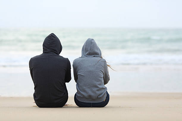 due adolescenti tristi seduti sulla spiaggia - sadness child little boys loneliness foto e immagini stock