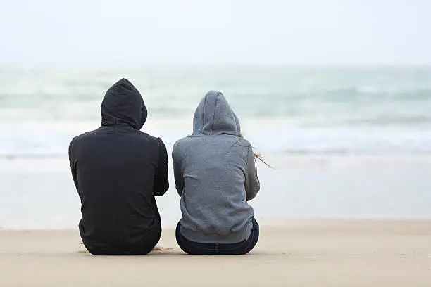 Photo of Two sad teenagers sitting on the beach