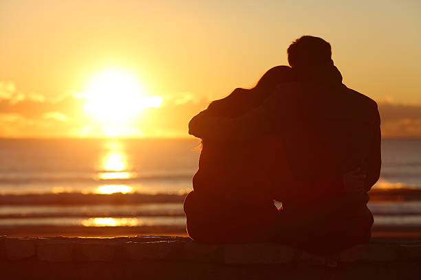 istock Couple watching sunset on the beach in winter 621379964