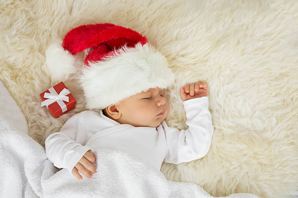 bambino che dorme con il cappello di natale e la confezione regalo - baby santa claus christmas sleeping foto e immagini stock