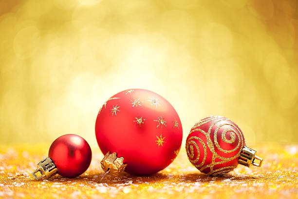 istock Red christmas baubles on gold glitter with yellow background 621382938
