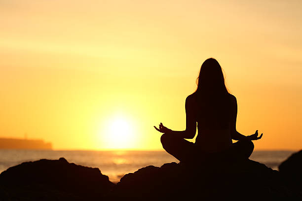 istock Woman silhouette doing yoga at sunrise 621383214