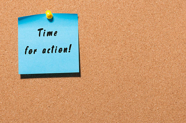 istock Time for Action written on blue sticker pinned to cork 621388972