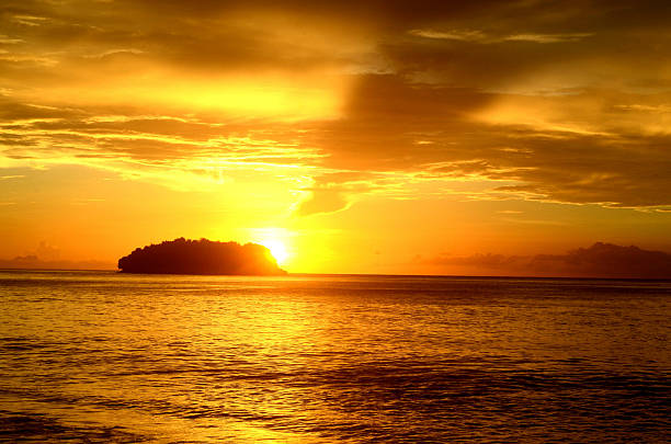 istock burning golden sunset and islet or island 621392850
