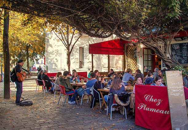 Paris, France  - October 31, 2016: A street musician is entertaining the guests at a small cafe in one of the more quiet streets of Montmartre, Paris.