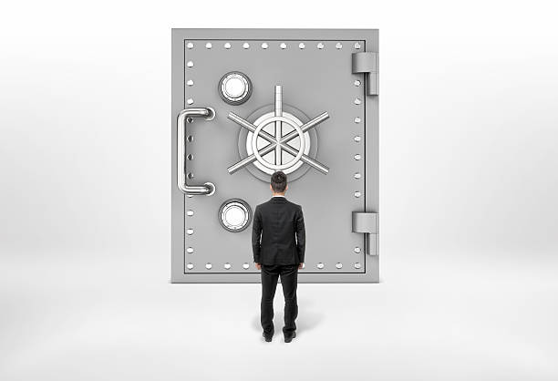 istock Businessman standing back to us looking at the giant safe 621461036