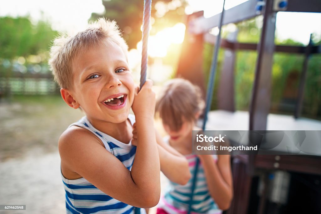 Kids laughing at the playground Kids sitting and hanging out at the playground.. Brother is aged 6 and the sister is 10. Kids are laughing happily. Sunny summer day evening . Child Stock Photo