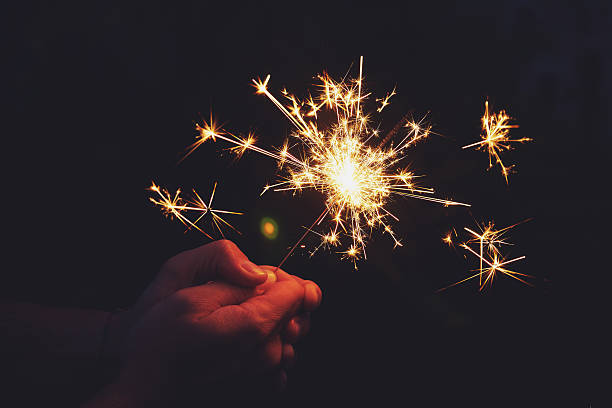 istock Man hands holding sparkler in the night. 621463724