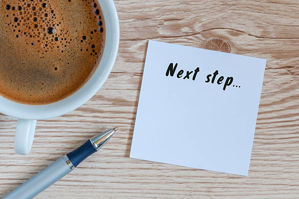 Next Steps inscription written in notepad near morning coffee cup
