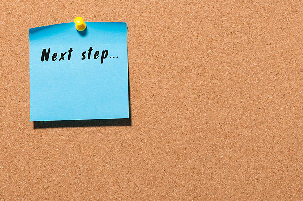 istock Next Steps inscription written on blue sticker pinned to cork 621464768
