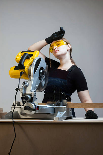 Tired female carpenter with a circular disk saw