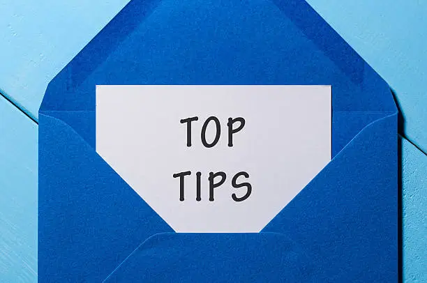 Photo of Text TOP TIPS on paper in blue envelope. Business concept