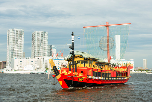 Tokyo, Japan - August 23, 2014: In front view beautiful oldfashioned tourist boat, vivid red and yellow, heading to the Odaiba. In background modern skyscrapers of Tokyo city. 