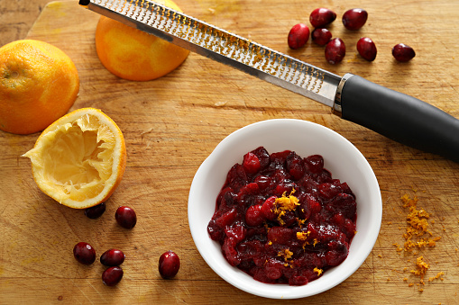 An overhead close up photograph of a small bowl of cranberry sauce with some freshly ground orange zest added.
