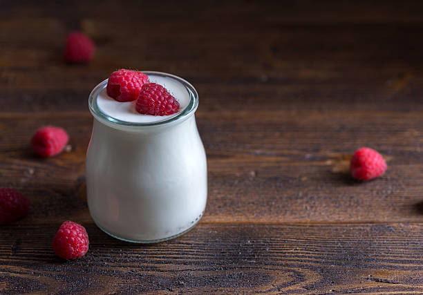 istock White yogurt with raspberries in glass bowl. 621472826