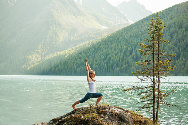istock Young woman is practicing yoga at mountain lake 621474920