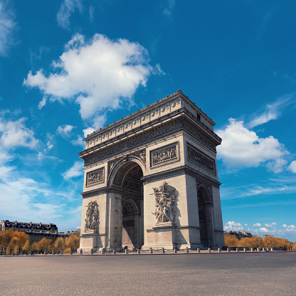 Arc de Triumph in Paris, France on a bright day under spectacular clouds. Vertical panorama image, all cars removed from the roundabout.