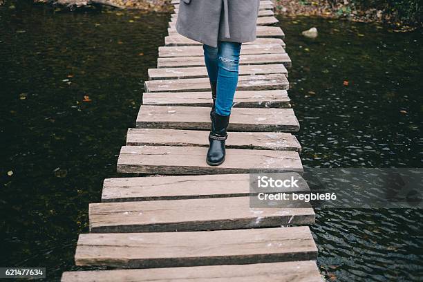 Young Woman Crossing A Wooden Bridge Stock Photo - Download Image Now - Adult, Autumn, Backpack
