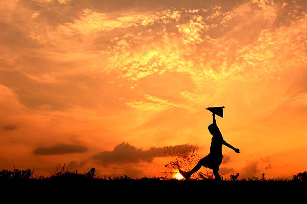 istock Silhouette a boy jumping with rocket paper 621478142