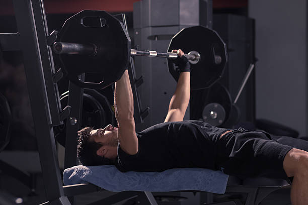 istock young man utility bench weights bar exercise fitness 621480120
