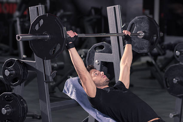 istock young man utility bench weights bar exercise fitness 621480416